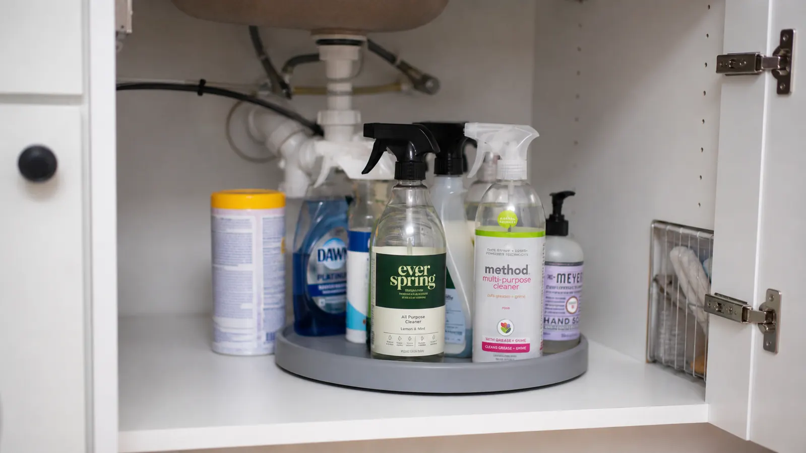 Bathroom vanity cabinet under the sink with cleaning bottles organized on a round turntable